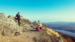 Caminantes femeninos encima de la montaña que toma una rotura y que disfruta de una opinión del valle Fotografía de archivo Caminantes femeninos encima de la montaña que toma una rotura y que disfruta de una opinión del valle Fotografía de archivo
