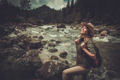 Caminhante da mulher que está perto do rio selvagem da montanha foto de stock Caminhante da mulher que está perto do rio selvagem da montanha foto de stock