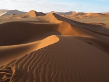 Camminando sulla linea curva naturale della cresta attraverso il modello del colpo del vento della duna di sabbia rossa arruggini fotografie stock Camminando sulla linea curva naturale della cresta attraverso il modello del colpo del vento della duna di sabbia rossa arruggini fotografie stock