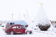 Campa bil för tappning som framme parkeras av iconic konkreta tipier av vigvammotellet 1937 under ett lager av nytt snowClassic b arkivfoto Campa bil för tappning som framme parkeras av iconic konkreta tipier av vigvammotellet 1937 under ett lager av nytt snowClassic b arkivfoto
