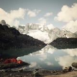 Campeggio vicino a retro effetto del lago alpino Tende variopinte Montagne di Caucaso Fotografia Stock Libera da Diritti Campeggio vicino a retro effetto del lago alpino Tende variopinte Montagne di Caucaso Fotografia Stock Libera da Diritti