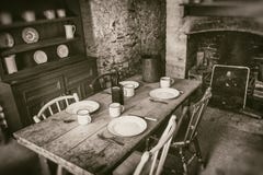 Campesinos pobres interiores de siglo XIX, de comedor con la tabla de madera determinada y de la chimenea, fotografía del estilo imagen de archivo Campesinos pobres interiores de siglo XIX, de comedor con la tabla de madera determinada y de la chimenea, fotografía del estilo imagen de archivo