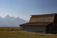 Campo di erba con il granaio e grandi montagne di Teton nel fondo immagini stock libere da diritti Campo di erba con il granaio e grandi montagne di Teton nel fondo immagini stock libere da diritti