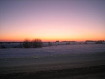 Campo nevado a lo largo del camino por la tarde del invierno en la puesta del sol imagen de archivo Campo nevado a lo largo del camino por la tarde del invierno en la puesta del sol imagen de archivo