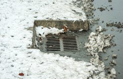 Canal o boca del dren de la lluvia en la calle en la ciudad para el agua rodeada con nieve en el invierno fotos de archivo Canal o boca del dren de la lluvia en la calle en la ciudad para el agua rodeada con nieve en el invierno fotos de archivo