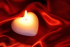 Candela a forma di del cuore su seta rossa Fotografia Stock Candela a forma di del cuore su seta rossa Fotografia Stock
