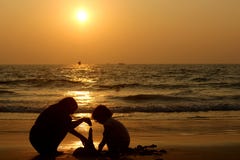 Candolim, Goa, Индия - 31-ое января 2017: диаграммы детей на океане на заходе солнца сделать пирамиду из влажного песка стоковые изображения Candolim, Goa, Индия - 31-ое января 2017: диаграммы детей на океане на заходе солнца сделать пирамиду из влажного песка стоковые изображения