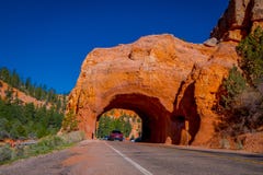 CANYON DE BRYCE, UTAH, JUIN, 07, 2018 : Belle vue extérieure des voitures croisant la voûte rouge située à l'entrée à photo libre de droits CANYON DE BRYCE, UTAH, JUIN, 07, 2018 : Belle vue extérieure des voitures croisant la voûte rouge située à l'entrée à photo libre de droits
