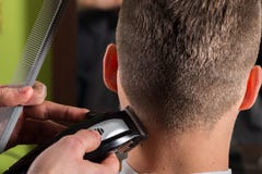 Capelli dei clienti di taglio del parrucchiere con una tosatrice elettrica fotografia stock Capelli dei clienti di taglio del parrucchiere con una tosatrice elettrica fotografia stock