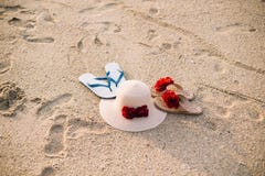 Cappello di paglia della spiaggia una coppia di Flip-flop Oggetti di estate sulla spiaggia sabbiosa immagine stock Cappello di paglia della spiaggia una coppia di Flip-flop Oggetti di estate sulla spiaggia sabbiosa immagine stock