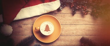Cappuccino with christmas hat and pine on table. stock photo Cappuccino with christmas hat and pine on table. stock photo