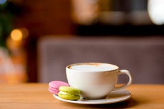 Cappuccino kawa w białej filiżance z kolorowymi macaroons słuzyć na drewnianym stole zdjęcie royalty free Cappuccino kawa w białej filiżance z kolorowymi macaroons słuzyć na drewnianym stole zdjęcie royalty free