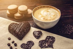 Cappuccino καφέ με τα όμορφες επόμενες macarons αφρού και την καρδιά σοκολάτας Στοκ φωτογραφίες με δικαίωμα ελεύθερης χρήσης Cappuccino καφέ με τα όμορφες επόμενες macarons αφρού και την καρδιά σοκολάτας Στοκ φωτογραφίες με δικαίωμα ελεύθερης χρήσης