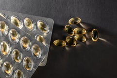 Capsules de l'huile de poisson omega3 et additif biologiquement actif de boursouflure sur un fond foncé, vue supérieure, légère d photo libre de droits Capsules de l'huile de poisson omega3 et additif biologiquement actif de boursouflure sur un fond foncé, vue supérieure, légère d photo libre de droits
