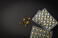 Capsules et boursouflure de l'huile de poisson omega3 sur une vue supérieure de plan rapproché foncé de fond photo stock Capsules et boursouflure de l'huile de poisson omega3 sur une vue supérieure de plan rapproché foncé de fond photo stock