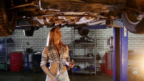Car repair service. A car lift. Young woman standing under the car and working with a wrench stock video Car repair service. A car lift. Young woman standing under the car and working with a wrench stock video