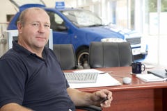 Car salesman sitting in showroom stock image Car salesman sitting in showroom stock image