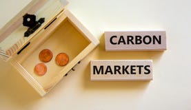 Carbon markets symbol. Concept words `carbon markets` on wooden blocks on a beautiful white background, small chest with coins.