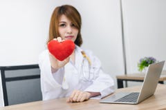 Cardiologist Asian female doctor with red heart in hands. Healthy care and medical concept. Selective focus and shallow depth of stock photography Cardiologist Asian female doctor with red heart in hands. Healthy care and medical concept. Selective focus and shallow depth of stock photography