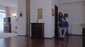 Care worker with young man in wheelchair at home stock video Care worker with young man in wheelchair at home stock video