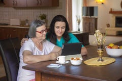 Caregiver με την ηλικιωμένη γυναίκα που χρησιμοποιεί την ψηφιακή ταμπλέτα στο σπίτι στοκ εικόνες Caregiver με την ηλικιωμένη γυναίκα που χρησιμοποιεί την ψηφιακή ταμπλέτα στο σπίτι στοκ εικόνες