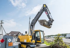 Cargador de excavador amarillo que se opone al cielo nublado soleado durante la construcción de carreteras y que repara trabajos fotografía de archivo libre de regalías Cargador de excavador amarillo que se opone al cielo nublado soleado durante la construcción de carreteras y que repara trabajos fotografía de archivo libre de regalías