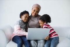 Mother with daughters using laptop in white studio
