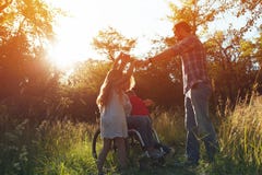 Woman in an armchair has fun with her husband and two children in park royalty free stock photo Woman in an armchair has fun with her husband and two children in park royalty free stock photo