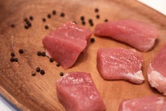 A carne cortou em partes o close-up em uma placa de madeira com pimentas picantes dos temperos fotografia de stock A carne cortou em partes o close-up em uma placa de madeira com pimentas picantes dos temperos fotografia de stock