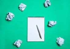 carnet blanc avec le stylo sur un fond vert parmi les boules de papier Le concept de produire des idées, inventant de nouvelles i photo stock carnet blanc avec le stylo sur un fond vert parmi les boules de papier Le concept de produire des idées, inventant de nouvelles i photo stock