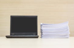 Carnet d'ordinateur de plan rapproché et pile noirs de papier de travail sur le mur en bois brouillé de bureau et en bois à l'arr image stock Carnet d'ordinateur de plan rapproché et pile noirs de papier de travail sur le mur en bois brouillé de bureau et en bois à l'arr image stock