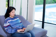 Carnet d'ordinateur de plan rapproché sur le sofa avec la femme asiatique pour le travail dans le mode de vie du concept de femme images libres de droits Carnet d'ordinateur de plan rapproché sur le sofa avec la femme asiatique pour le travail dans le mode de vie du concept de femme images libres de droits