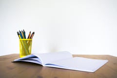 Carnet et verre avec des crayons et des stylos sur une table en bois Front View image libre de droits Carnet et verre avec des crayons et des stylos sur une table en bois Front View image libre de droits