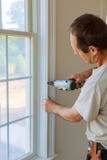 Carpenter brad using nail gun to moldings on windows, framing trim, Stock Photography Carpenter brad using nail gun to moldings on windows, framing trim, Stock Photography