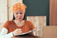 Carpintero de sexo femenino que escribe notas del proyecto de DIY imagen de archivo libre de regalías Carpintero de sexo femenino que escribe notas del proyecto de DIY imagen de archivo libre de regalías