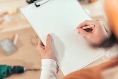 Carpintero de sexo femenino que escribe notas del proyecto de DIY imágenes de archivo libres de regalías Carpintero de sexo femenino que escribe notas del proyecto de DIY imágenes de archivo libres de regalías