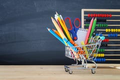 Carrinho de compras com fonte de escola na frente do quadro-negro De volta ao conceito da escola imagens de stock Carrinho de compras com fonte de escola na frente do quadro-negro De volta ao conceito da escola imagens de stock