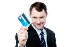 Carta di credito allegra della tenuta dell'uomo d'affari fotografia stock libera da diritti Carta di credito allegra della tenuta dell'uomo d'affari fotografia stock libera da diritti