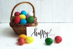 Carte de Pâques avec les oeufs de pâques colorés dans un ` heureux de Pâques de panier et de ` calligraphique d'inscription photographie stock libre de droits Carte de Pâques avec les oeufs de pâques colorés dans un ` heureux de Pâques de panier et de ` calligraphique d'inscription photographie stock libre de droits