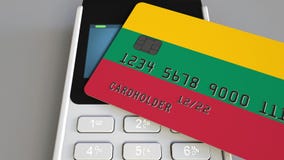 Cartão de banco plástico que caracteriza a bandeira de Lituânia e do terminal do pagamento da posição Sistema bancário lituano ou video estoque Cartão de banco plástico que caracteriza a bandeira de Lituânia e do terminal do pagamento da posição Sistema bancário lituano ou video estoque