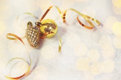 Cartão de Natal bola dourada das decorações do Natal, pinecone, fita dourada em um fundo branco com neve e luzes suaves fotografia de stock Cartão de Natal bola dourada das decorações do Natal, pinecone, fita dourada em um fundo branco com neve e luzes suaves fotografia de stock