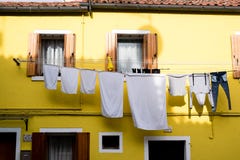 Casa amarela brilhante com obturadores e suspensão de lavagem para fora na ilha de Burano, Veneza imagem de stock royalty free Casa amarela brilhante com obturadores e suspensão de lavagem para fora na ilha de Burano, Veneza imagem de stock royalty free