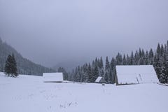 A casa de madeira está em um vale nevado, uma montanha no backgro fotografia de stock A casa de madeira está em um vale nevado, uma montanha no backgro fotografia de stock