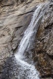 Cascade en bas de la falaise pure de roche frappant l'obstruction et pulvérisant en longueur entouré par la roche humide images stock Cascade en bas de la falaise pure de roche frappant l'obstruction et pulvérisant en longueur entouré par la roche humide images stock