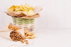 Casse-croûte colorés d'or - nachos, maïs éclaté, croûtons, pommes chips dans le panier rustique et cône de papier de métier sur l photo libre de droits Casse-croûte colorés d'or - nachos, maïs éclaté, croûtons, pommes chips dans le panier rustique et cône de papier de métier sur l photo libre de droits