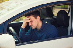 Casual young guy driver experiencing headache, should stop the car after driving in a traffic jam