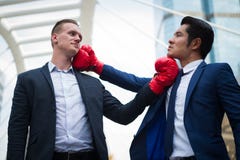 Caucasian affärsman och asiataffärsman med röda boxninghandskar som slåss vid uppercut till hakan Begrepp av affärskonkurrens royaltyfri bild Caucasian affärsman och asiataffärsman med röda boxninghandskar som slåss vid uppercut till hakan Begrepp av affärskonkurrens royaltyfri bild