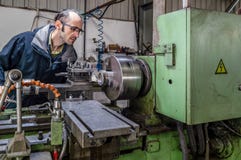 Caucasian engineer watching the headstock of turning lathe machine in factory stock photo Caucasian engineer watching the headstock of turning lathe machine in factory stock photo