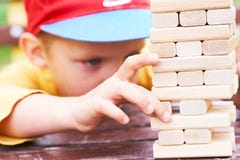 Caucasian kid is playing wood blocks tower game for practicing physical and mental skill. stock photos Caucasian kid is playing wood blocks tower game for practicing physical and mental skill. stock photos