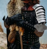 Cavaleiro medieval com a espada na armadura nos forestholds a espada um homem na armadura, com um casaco do lobo jogos do traje foto de stock Cavaleiro medieval com a espada na armadura nos forestholds a espada um homem na armadura, com um casaco do lobo jogos do traje foto de stock